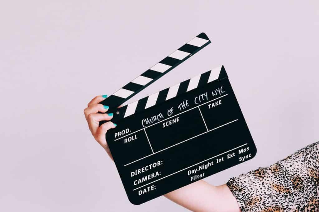 A woman holding up a movie clapper board while learning German online.