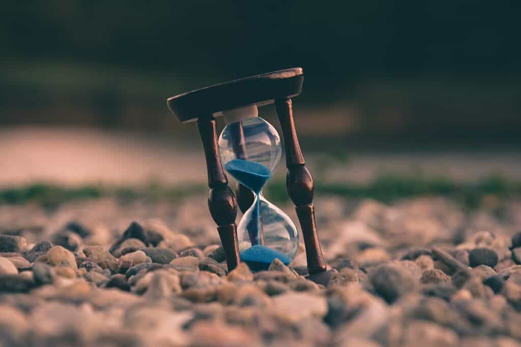 A sand hourglass, ideal for those looking to learn German online or through German learning methods, sitting gracefully on the ground.