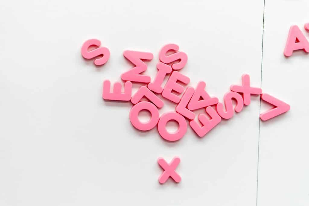 Pink letters arranged on a white wall for a creative German learning environment.