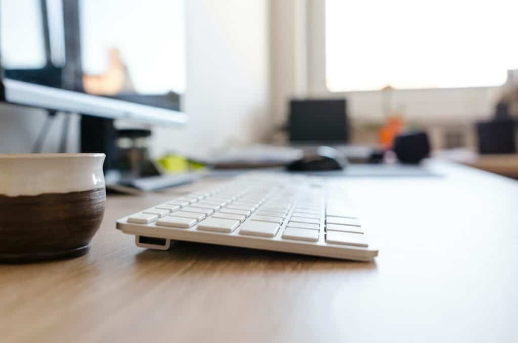 A desk with a keyboard, where you can learn German online while sipping on a cup of coffee.