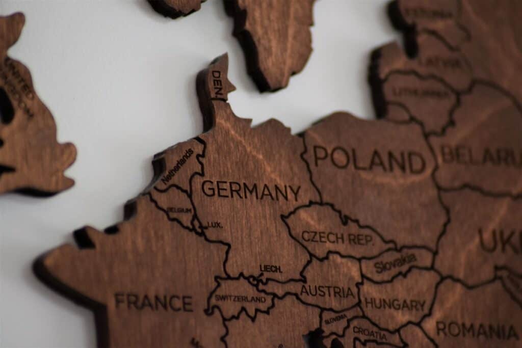 A wooden map of the world on a wall, serving as a captivating visual aid for those looking to learn German online or enhance their German learning journey.