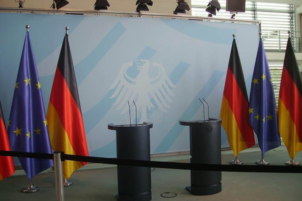 Three podiums with German and EU flags in front of them, highlighting the importance of German learning.