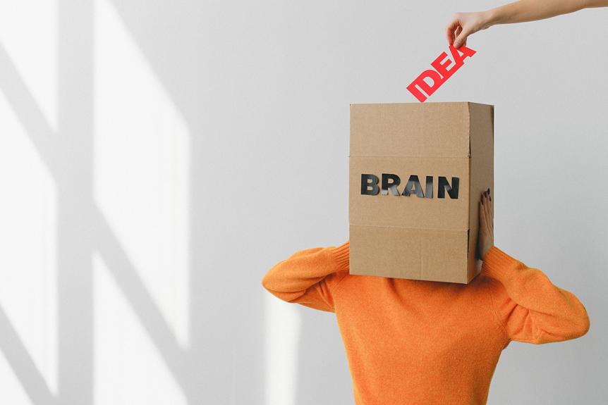A person holding a cardboard box with the word "brain" on it, representing their dedication to learn German online.
